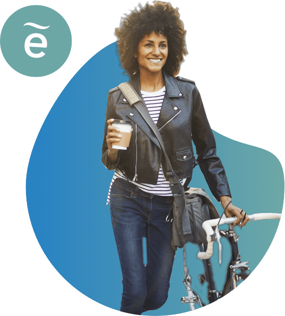Mujer joven, moderna, con un café en una mano y empujando una bicicleta con la otra.